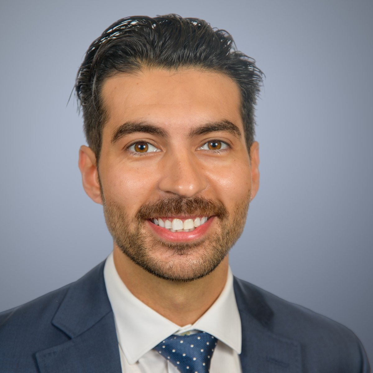 Portrait of Dr. Mark Michael in a navy suit against a blue-grey backdrop